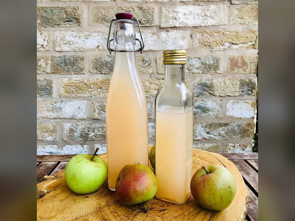 Botellas de sidra junto a manzanas